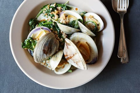 A bowl of clams with greens