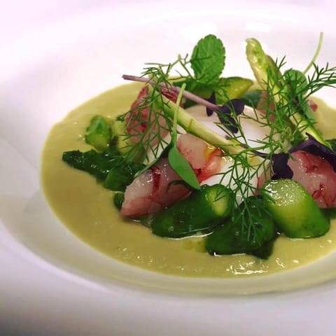 Raw shrimp and asparagus tips on a pale green asparagus cream