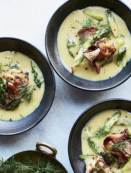 Bowls of white asparagus soup with herbs and mushrooms