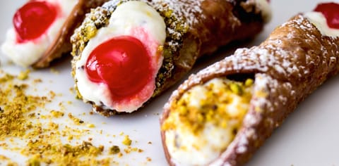 Sicilian cannoli filled with ricotta, finished with pistachio and candied cherries
